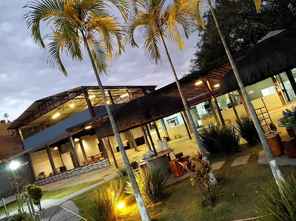 Jardim com palmeiras e quiosques iluminados ao entardecer