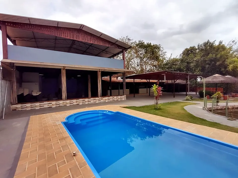 Piscina azul ao lado da área coberta e do gramado